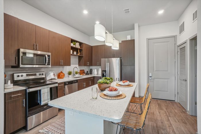 Modern kitchen with sleek appliances, chic wooden cabinets, and an elegant island bar with stylish seating, perfect for entertaining.