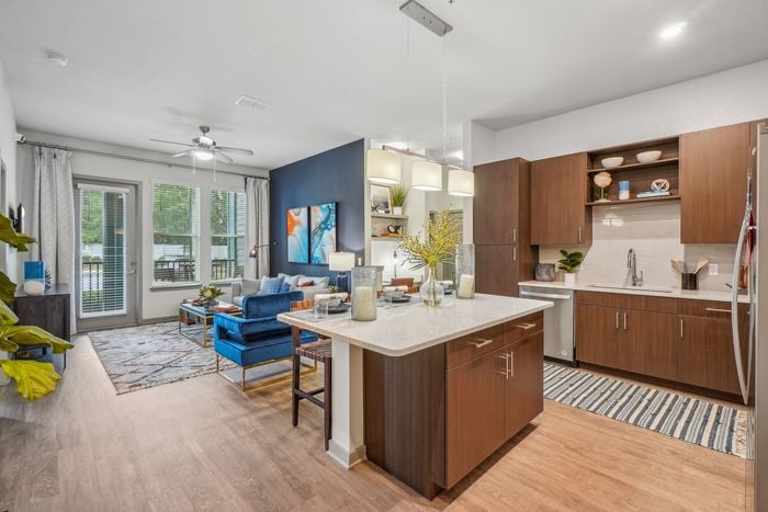 Modern open-concept living space featuring a stylish kitchen with a central island, elegant cabinetry, and cozy lounge area with vibrant decor and large windows.