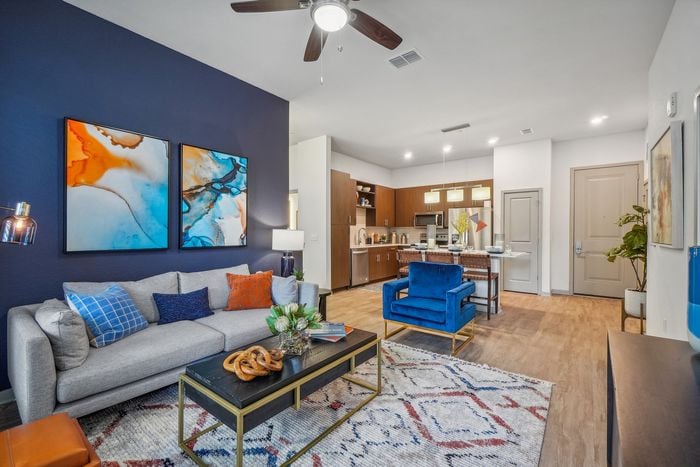 Contemporary open-concept apartment with a cozy living area, stylish blue accents, and a modern kitchen island with sleek finishes.