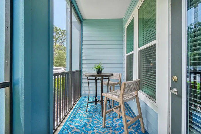Charming balcony with stylish seating and vibrant blue rug, perfect for relaxation and enjoying outdoor views.