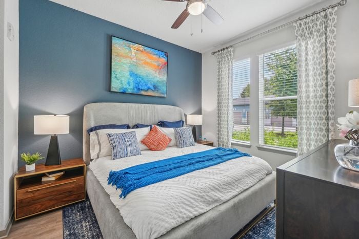 Bright and inviting bedroom with a plush bed, modern decor, large windows, and elegant wall art.
