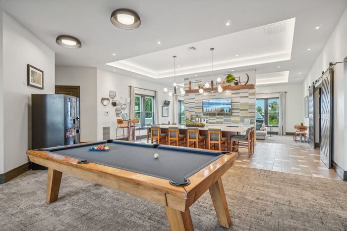 Inviting apartment lounge with a modern pool table, stylish seating, and vibrant lighting perfect for entertaining.
