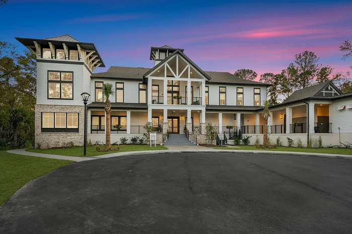 Elegant two-story luxury apartment complex with beautiful architectural design, featuring a grand entrance and tranquil surroundings at sunset.