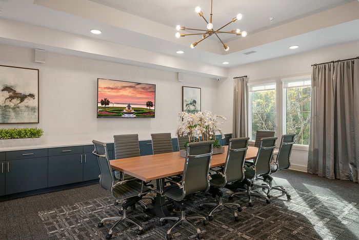 Elegant conference room with modern seating, stylish chandelier, and natural light pouring through large windows.