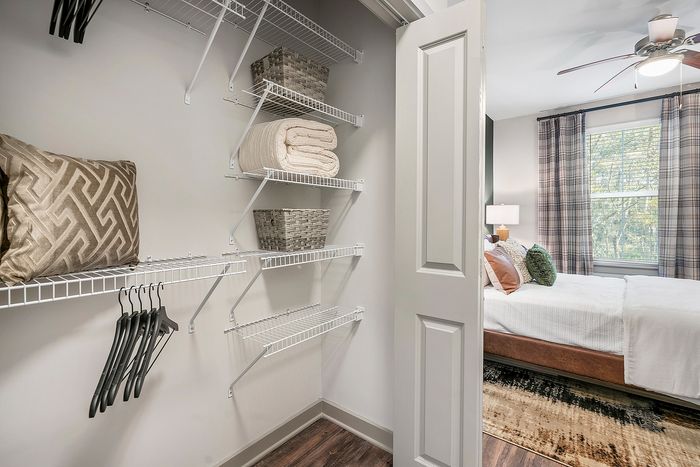 Chic walk-in closet with modern shelving, premium storage baskets, and cozy bedroom view.