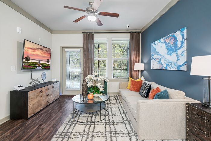 Contemporary living room featuring a cozy beige sofa with colorful cushions, stylish decor, and natural light streaming through large windows.