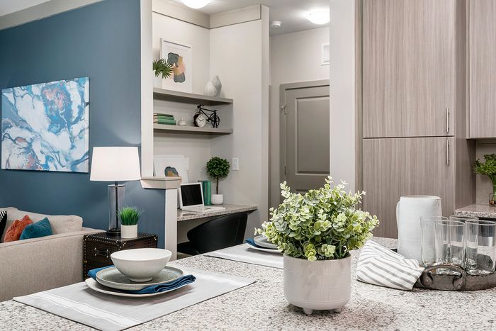 Chic modern kitchen with sleek granite countertops, elegant dining setup, and stylish open shelving in a cozy apartment.
