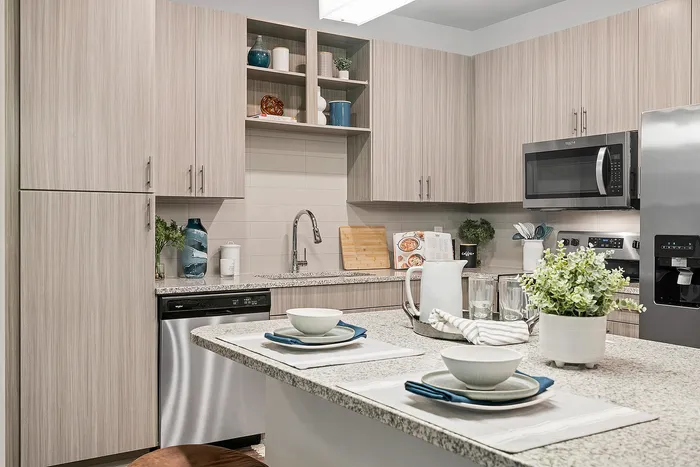Modern kitchen with sleek cabinetry, granite countertops, and stainless steel appliances, featuring an inviting breakfast bar setup.