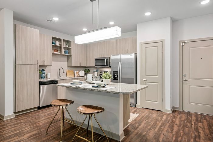 Modern kitchen with sleek cabinetry, stainless steel appliances, and an inviting island countertop with two stylish stools, perfect for gatherings.
