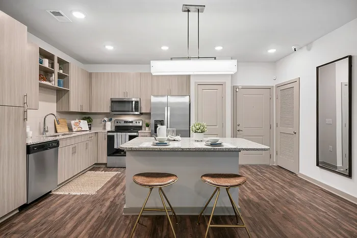 Modern kitchen with sleek cabinetry, stainless steel appliances, and an inviting island countertop with two stylish stools, perfect for gatherings.