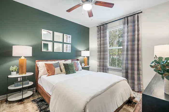 Elegant bedroom with stylish decor, featuring a plush bed, modern lamps, and a green accent wall, offering a cozy and inviting atmosphere.
