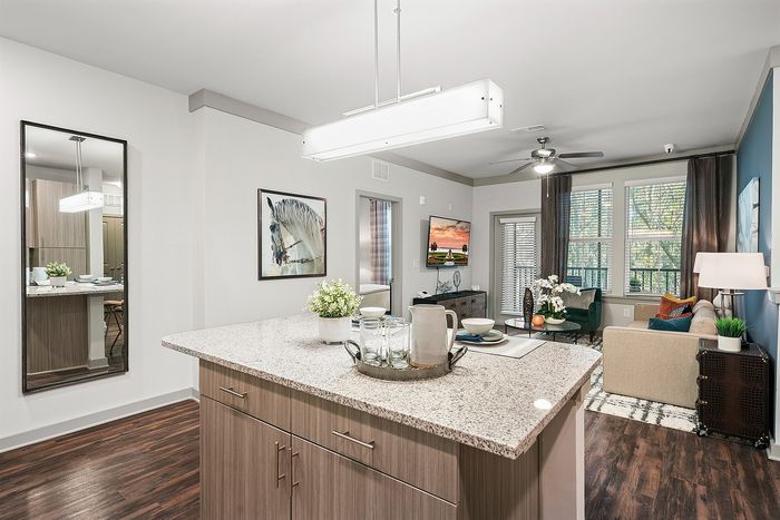 Elegant open-plan living area featuring a stylish kitchen island, cozy living room with modern decor, and large windows offering natural light.