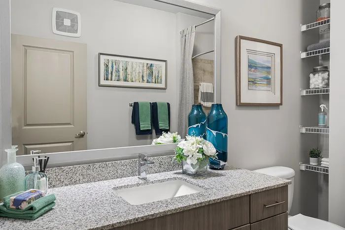 Elegant bathroom with granite countertop, stylish blue vases, and modern fixtures, providing a serene and luxurious atmosphere.