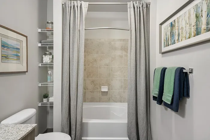 Modern bathroom with elegant shower, neutral tiles, and stylish shelving in a chic apartment.