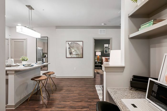 Modern apartment interior with a sleek kitchen bar, cozy bedroom, and stylish home office space, perfect for urban living.