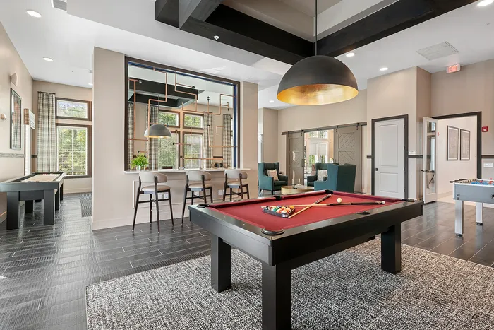 Luxurious game room with a stylish pool table, cozy seating area, and a modern bar with chic lighting.