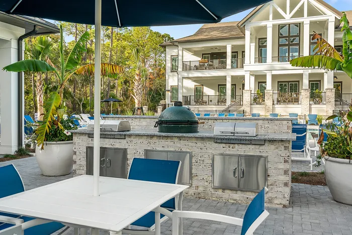 Luxurious outdoor living space featuring a modern barbecue area, stylish patio seating, and a beautiful view of a grand villa with a spacious balcony.
