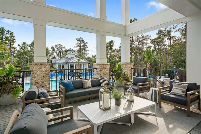 Elegant outdoor patio with stylish seating and pool view, surrounded by lush greenery and modern decor.