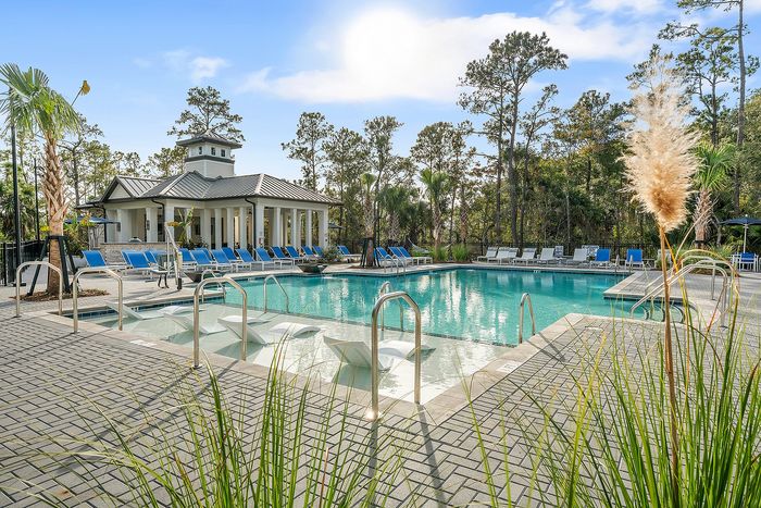 Inviting resort-style pool with elegant lounge chairs and lush greenery, perfect for relaxation in a tranquil setting.