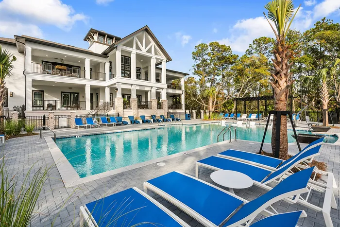 Luxurious apartment complex featuring a sparkling swimming pool, surrounded by modern lounging areas and elegant architectural design.