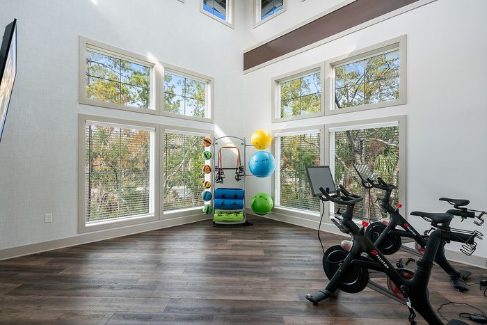 Bright and inviting home gym with large windows, featuring exercise bikes and vibrant fitness equipment for a dynamic workout experience.
