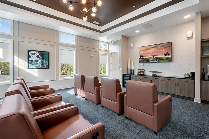 Elegant and cozy apartment media room with plush seating, contemporary lighting, and a large wall-mounted TV, perfect for entertainment.