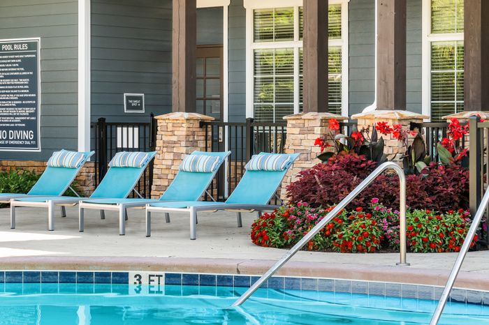 Inviting poolside oasis with vibrant lounge chairs and colorful floral landscaping, perfect for relaxation and leisure.