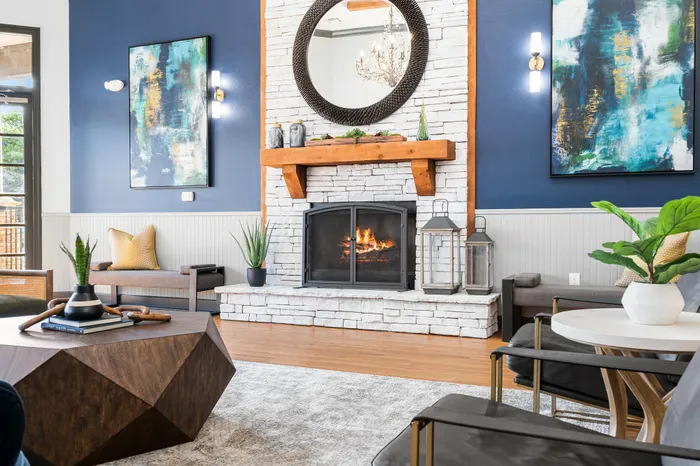 Chic and inviting living room featuring a modern stone fireplace, elegant decor, and abundant natural light.