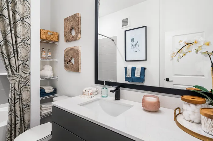 Bright and elegant bathroom featuring a modern vanity with chic decor, lush towels, and stylish wooden accents, creating a cozy and inviting atmosphere.