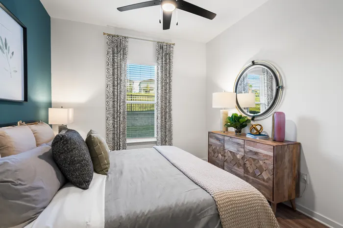 Chic bedroom with a cozy bed, stylish dresser, and elegant decor, bathed in natural light. Comfortable and modern living.