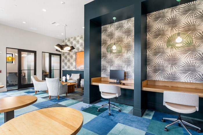 Trendy co-working space with chic decor, featuring modern desks, comfortable seating, and vibrant geometric carpet.