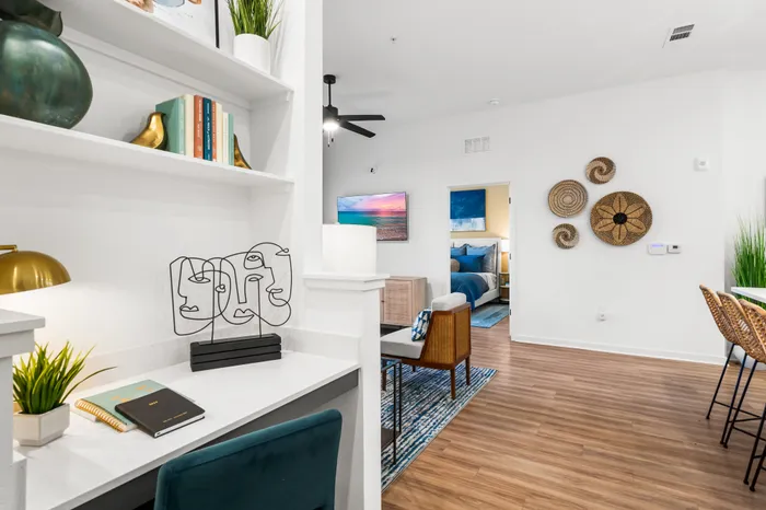 Elegant apartment interior featuring a cozy workspace with stylish decor, open-concept living area with modern art, and inviting bedroom view.