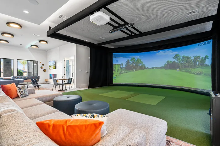 Luxurious entertainment room featuring a state-of-the-art golf simulator, plush seating area, and stylish decor.