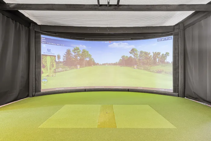 Luxurious home golf simulator with immersive curved screen and lush green artificial turf.