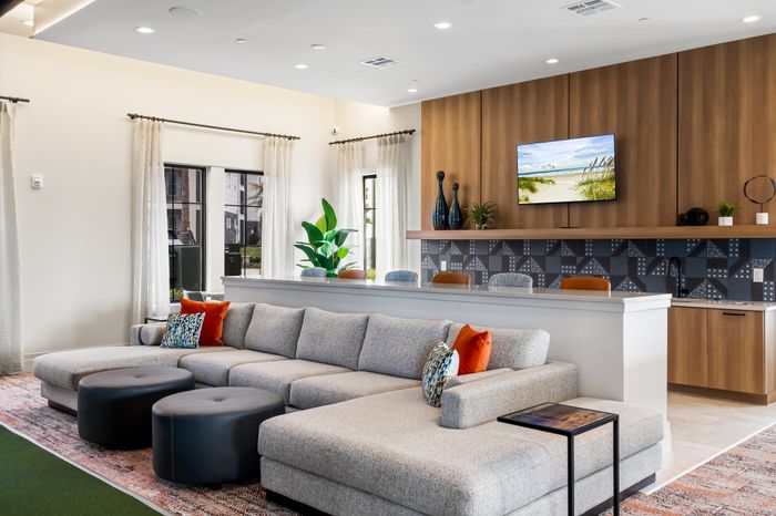 Luxurious open-concept lounge with a stylish gray sectional sofa, vibrant cushions, and chic modern decor, perfect for relaxing and socializing.