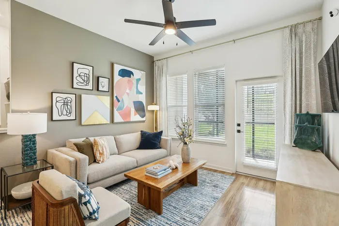 Bright and inviting living room featuring modern art, cozy beige sofa, elegant decor, and natural light streaming through large windows.