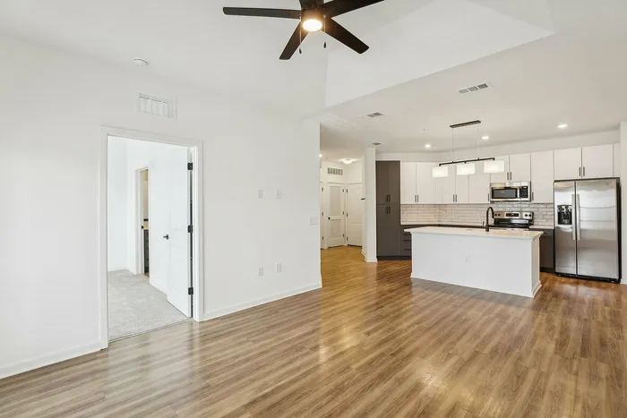 Contemporary open-plan kitchen and living area with sleek appliances, wood flooring, and elegant lighting.