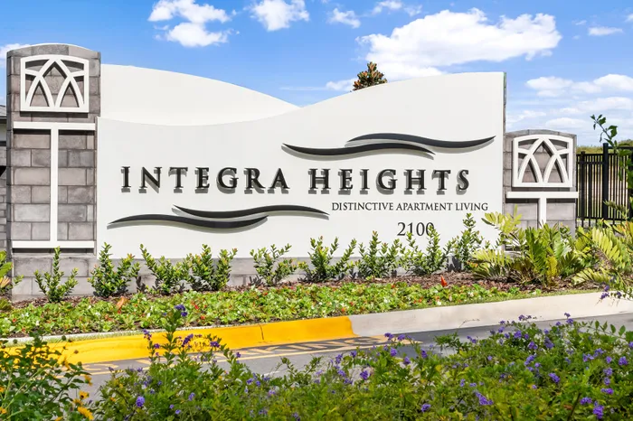 Elegant signage for Integra Heights, highlighting distinctive apartment living with manicured landscaping and vibrant flowers.