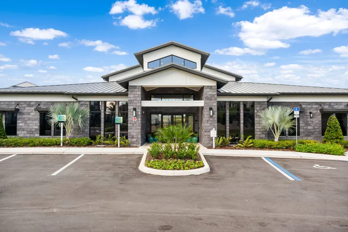 Elegant modern building with striking architecture, large windows, and lush landscaping under a clear blue sky.
