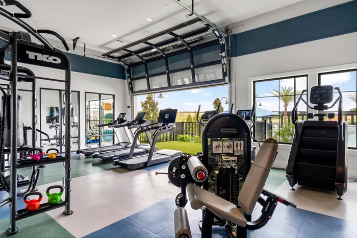 Modern fitness center with state-of-the-art equipment, featuring treadmills, weights, and an outdoor view promoting an active lifestyle.