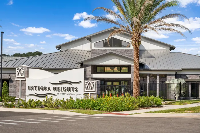 Elegant entrance of Integra Heights showcasing modern architecture, lush landscaping, and a welcoming ambiance under a clear blue sky.