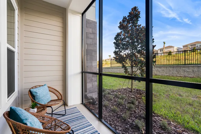 Charming, screened-in patio with cozy wicker chairs and garden view.