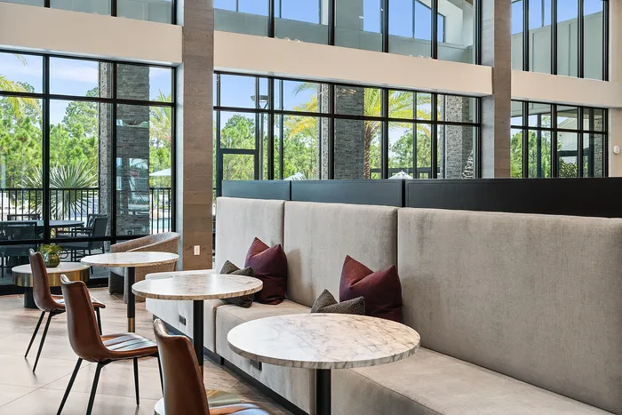 Modern lounge area with elegant marble tables, cozy seating, and floor-to-ceiling windows offering scenic outdoor views.
