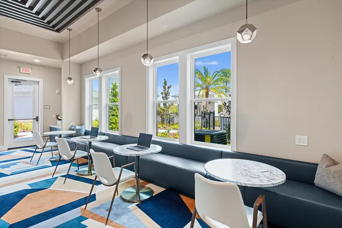 Bright and inviting workspace with modern seating, geometric carpet, and large windows overlooking lush greenery.