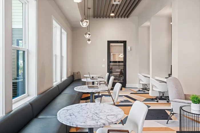 Modern and inviting communal seating area with elegant marble tables, plush seating, and sleek pendant lighting, perfect for relaxation or casual work sessions.