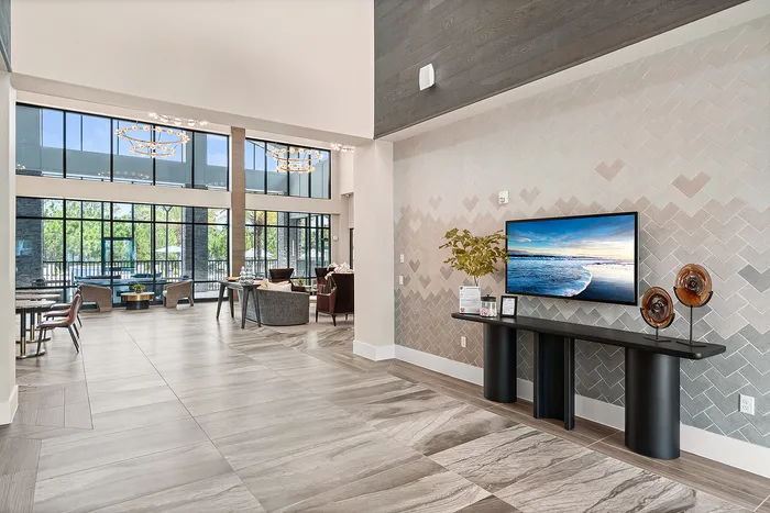 Luxurious apartment lobby featuring modern decor, high ceilings, and expansive windows overlooking a scenic view.