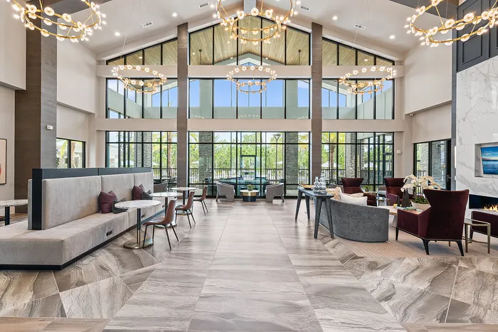 Luxurious and spacious apartment lounge with high ceilings, elegant chandeliers, modern seating, and expansive windows offering breathtaking natural light.