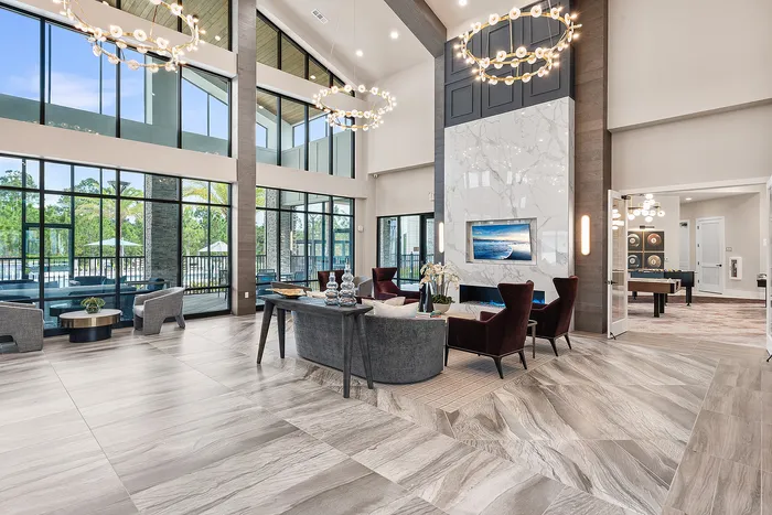Luxurious modern living space featuring high ceilings, elegant chandeliers, and expansive windows with poolside views.