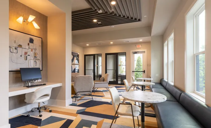 Modern and inviting shared workspace with stylish decor, featuring comfortable seating, marble tables, and a contemporary computer station.