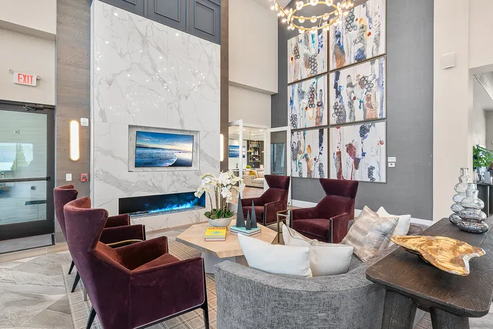Luxurious lounge featuring elegant velvet chairs, modern art pieces, and a sleek marble fireplace creating an inviting, stylish ambiance.